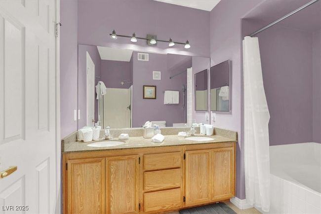 Bathroom featuring curtained shower, a bathing tub, double vanity, and a sink | Image 22
