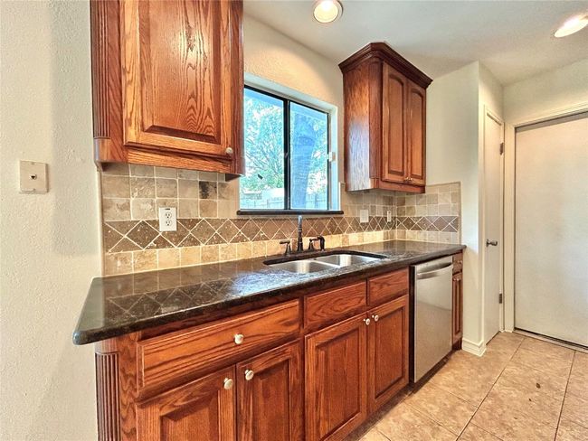 Kitchen with dishwasher, tasteful backsplash, brown cabinetry, light tile patterned floors, and a textured wall | Image 8