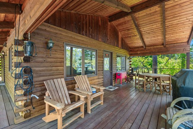 Covered wooden deck area featuring outdoor dining area | Image 19