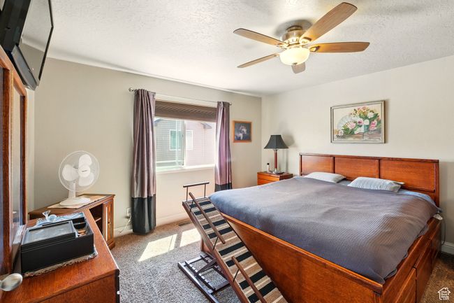 Bedroom featuring carpet floors, baseboards, a textured ceiling, and ceiling fan | Image 14