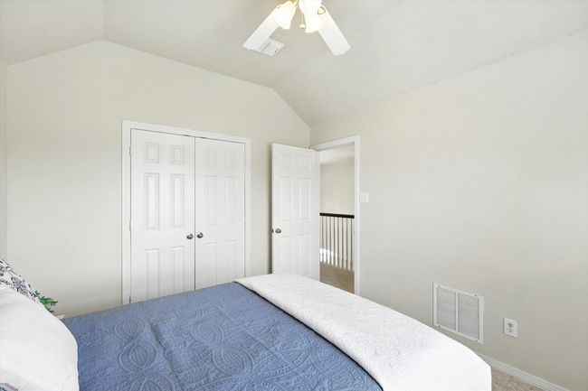 Carpeted bedroom featuring lofted ceiling, a closet, and ceiling fan | Image 25