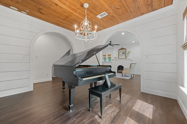 Living area featuring arched walkways, wooden ceiling, a brick fireplace, wood finished floors, and a ceiling fan | Image 10