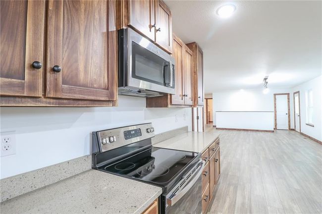 Kitchen featuring light stone counters, stainless steel appliances, and light hardwood / wood-style floors | Image 15