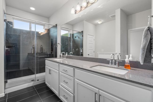 Bathroom featuring tile patterned floors, double vanity, a stall shower, and recessed lighting | Image 16