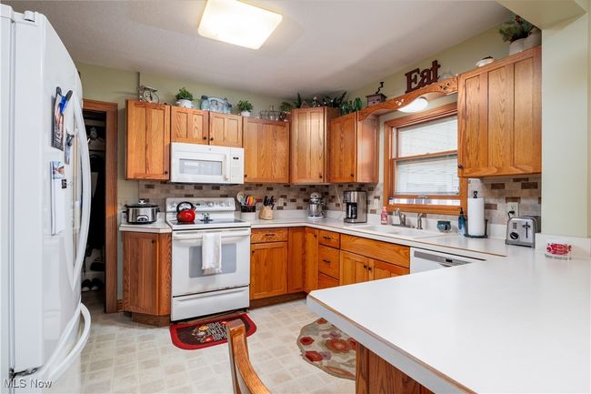 Kitchen featuring light countertops, tasteful backsplash, a sink, and white appliances | Image 17