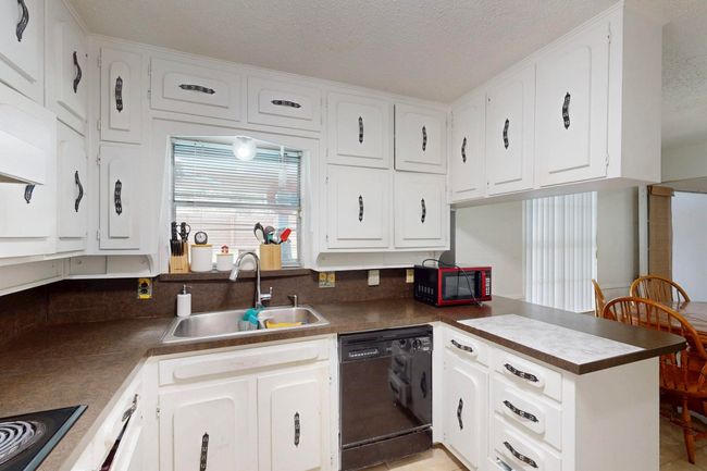 Kitchen featuring electric cooktop, a sink, dishwasher, white cabinets, and a peninsula | Image 12