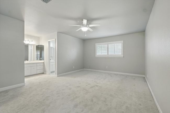 Primary bedroom with baseboards, light colored carpet, and with an extra vanity outside full bathroom | Image 21
