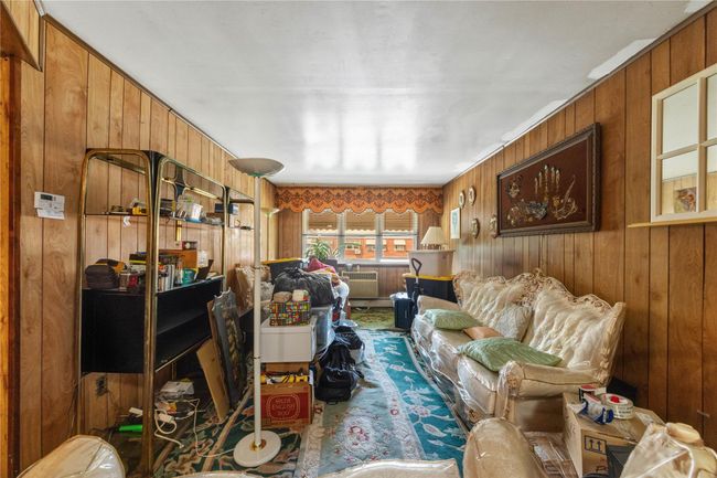 Living area with wooden walls and carpet flooring | Image 8