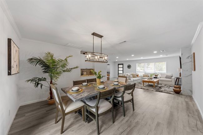 Dining area with ornamental molding, light wood-type flooring, a chandelier, and recessed lighting | Image 5