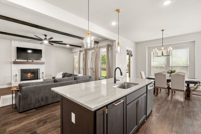 Kitchen featuring stainless steel dishwasher, dark wood-style floors, a fireplace, decorative light fixtures, and recessed lighting | Image 8