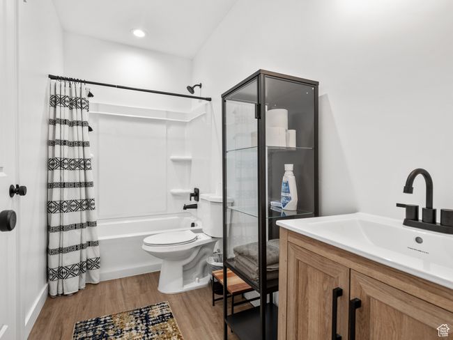 Full bathroom featuring shower / bath combination with curtain, wood finished floors, and vanity | Image 34