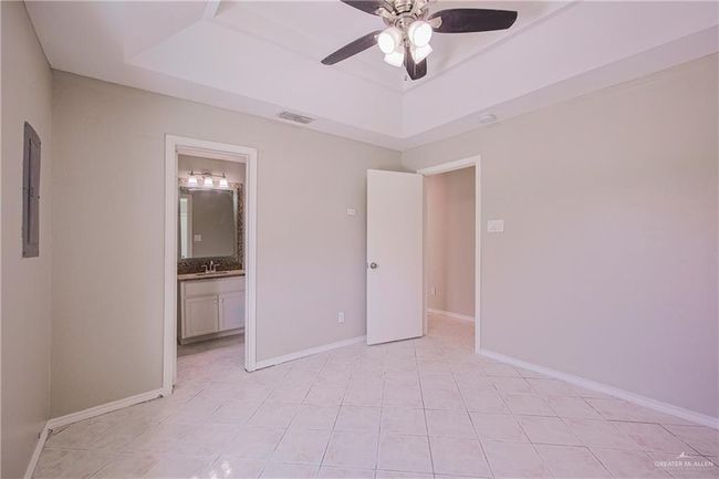 Unfurnished bedroom with a sink, visible vents, a tray ceiling, baseboards, and ensuite bath | Image 15