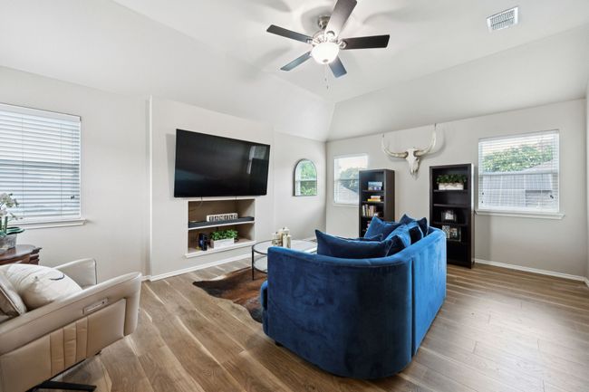 Living or game room area with a ceiling fan, healthy amount of natural light, wood finished floors, and lofted ceiling | Image 28