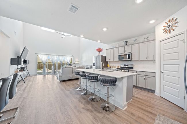 Kitchen featuring visible vents, a sink, open floor plan, a breakfast bar, and stainless steel appliances | Image 8