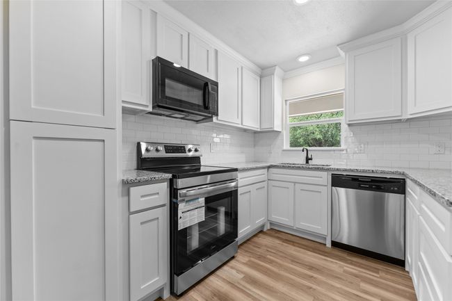 Kitchen with appliances with stainless steel finishes, a sink, white cabinetry, decorative backsplash, and recessed lighting | Image 5