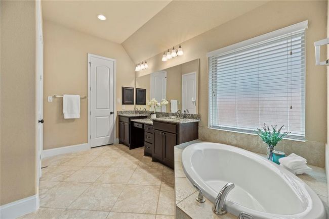 The primary bath features a soaking tub, shower, two sinks and a vanity area. There are also 2 walk-in closets. | Image 28