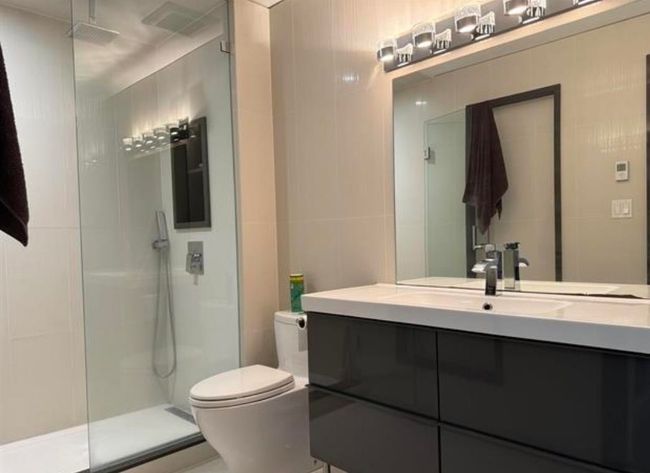 Bathroom featuring tile walls, toilet, a walk in shower, and vanity | Image 4