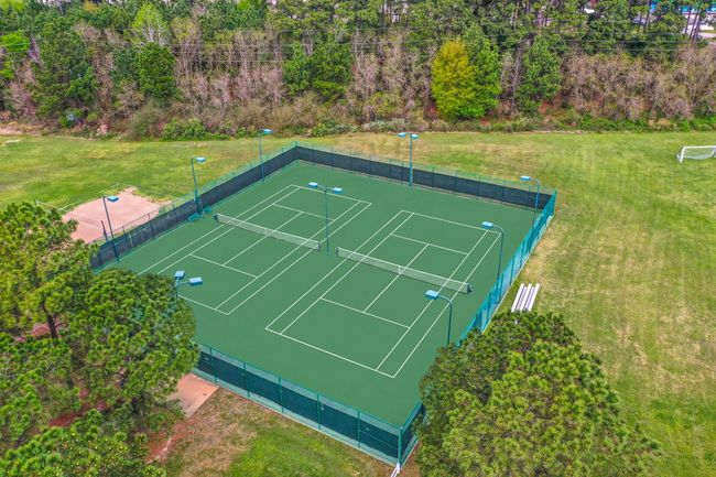 Enjoy an aerial view of our community tennis courts in Windrose, where residents can engage in friendly matches and stay active. Part of a vibrant community hub that also features pools, a Meeting House, and ample green space for all your recreational needs. | Image 46