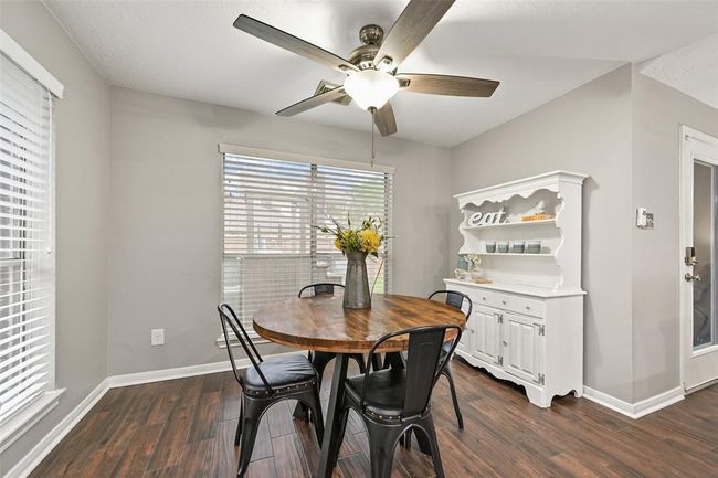 Enjoy a casual meal in this bright & cheerful breakfast area with wood-look tile floors, a ceiling fan, and plenty of natural light—perfect for casual meals or morning coffee with a view of the backyard. | Image 7