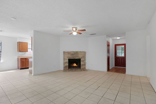 Unfurnished living room with a ceiling fan and brick fireplace | Image 8