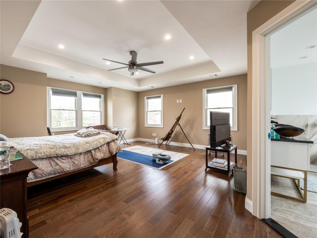 Bedroom with wood-type flooring, a raised ceiling, baseboards, and recessed lighting | Image 16