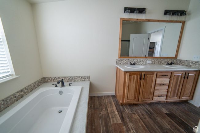 Bathroom featuring a bath, wood finished floors, a sink, and double vanity | Image 11