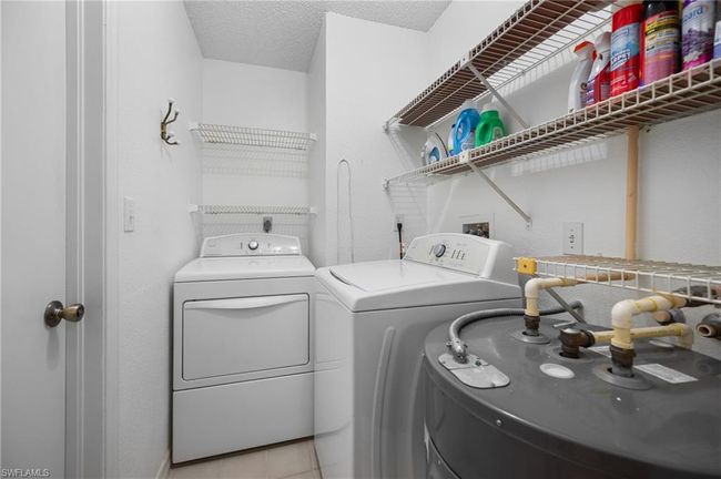 Washroom with washer and dryer, water heater, a textured ceiling, and light tile patterned floors | Image 21