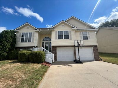 Bi-level home featuring a garage and a front lawn | Image 1