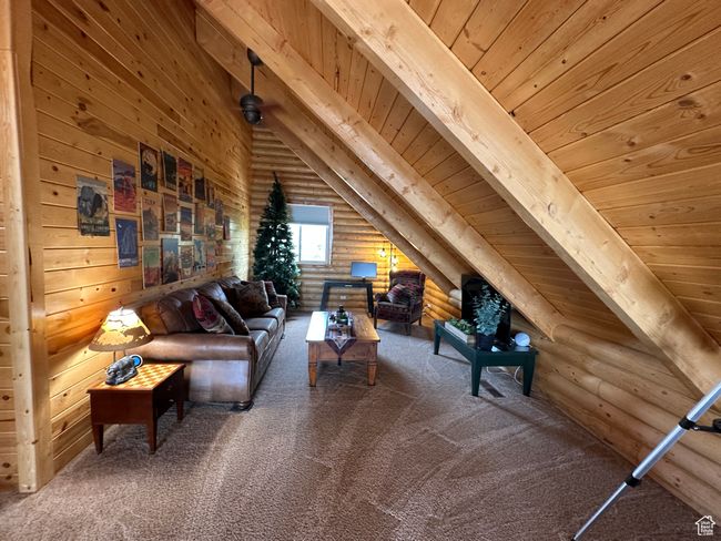 Living area featuring carpet flooring, wood ceiling, vaulted ceiling with beams, and rustic walls | Image 9