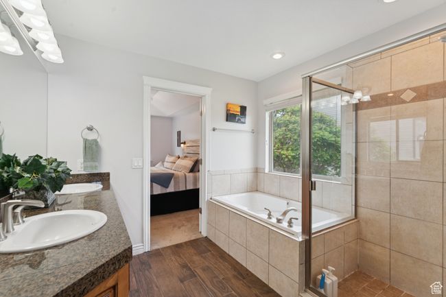 Ensuite bathroom featuring double vanity, wood finished floors, a stall shower, a garden tub, and recessed lighting | Image 16