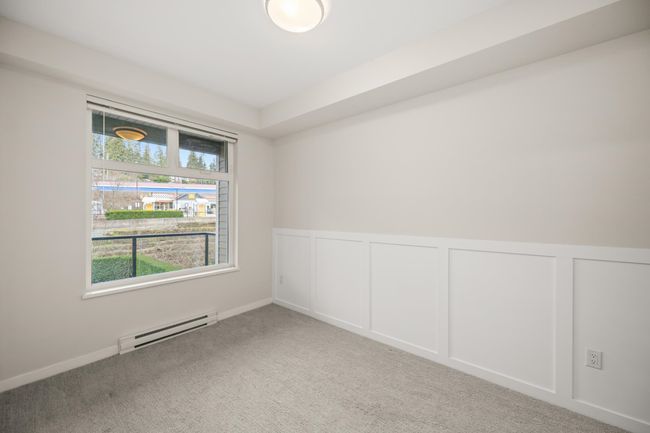 Carpeted empty room with baseboard heating, a decorative wall, and a wainscoted wall | Image 26