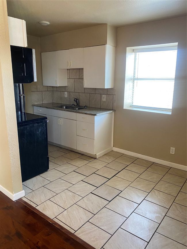 Kitchen with white cabinets, a sink, backsplash, and baseboards | Image 4