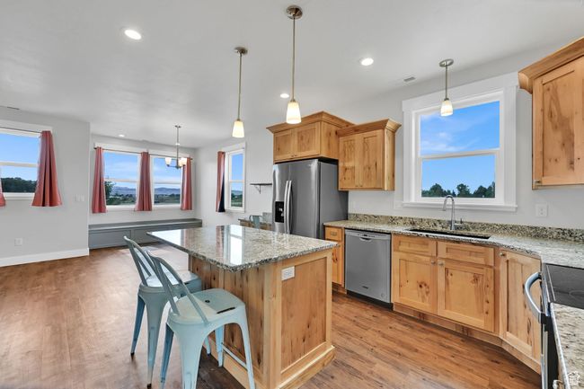 Kitchen featuring appliances with stainless steel finishes, a kitchen island, light wood finished floors, light stone countertops, and recessed lighting | Image 51