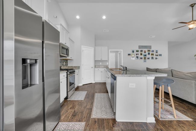 Kitchen with stainless steel appliances, a ceiling fan, a sink, a kitchen island with sink, and open floor plan | Image 22