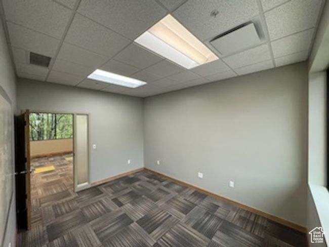 Unfurnished room with a drop ceiling and dark carpet | Image 27