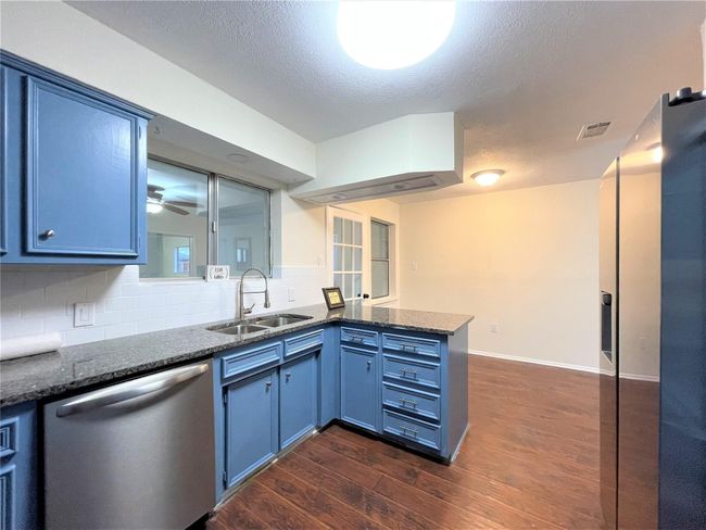 Kitchen featuring dishwasher, a peninsula, blue cabinetry, dark wood finished floors, and tasteful backsplash | Image 13