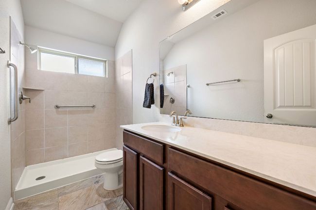 Bathroom with tiled shower, visible vents, vanity, and toilet | Image 20