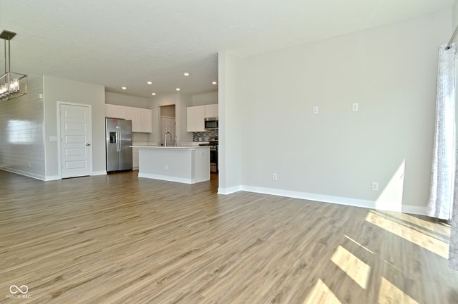 unfurnished living room featuring light wood-type flooring, an inviting chandelier, baseboards, and recessed lighting | Image 9