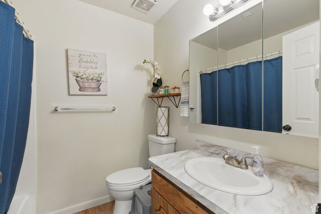 Full bath featuring wood finished floors, vanity, a shower with curtain, toilet, and visible vents | Image 29