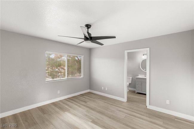 Unfurnished bedroom featuring ensuite bath, light wood finished floors, baseboards, and ceiling fan | Image 23