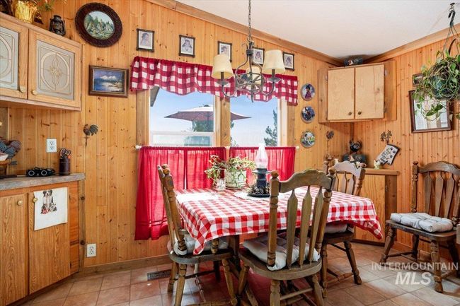 Dining space with wood walls, light tile patterned floors, and a chandelier | Image 18