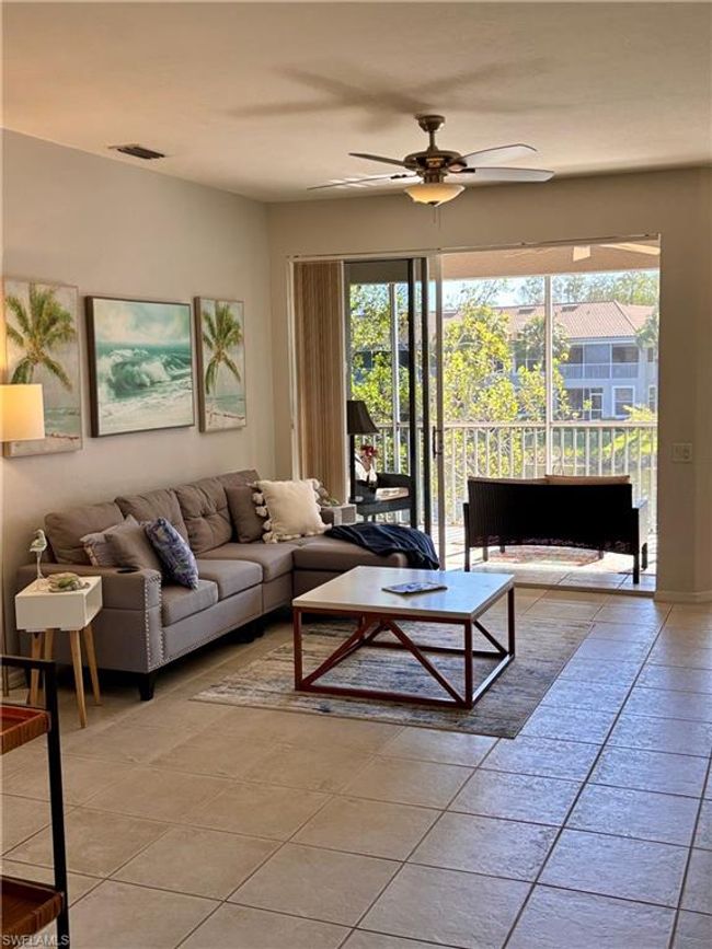 Living room with tile flooring leads has a triple slider that leads out to the screened lanai. | Image 9