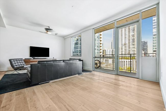 Unfurnished living room with a city view, wood finished floors, and baseboards | Image 4