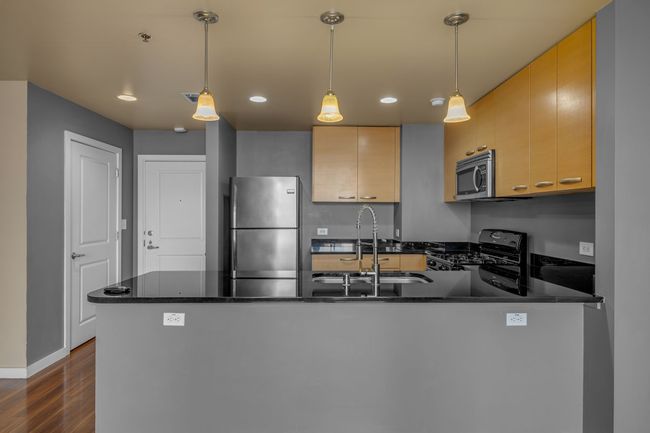 Kitchen with a sink, stainless steel appliances, a peninsula, dark wood-style floors, and recessed lighting | Image 5