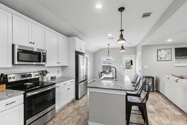 Kitchen featuring stainless steel appliances, a sink, light wood-type flooring, open floor plan, and white cabinetry | Image 11