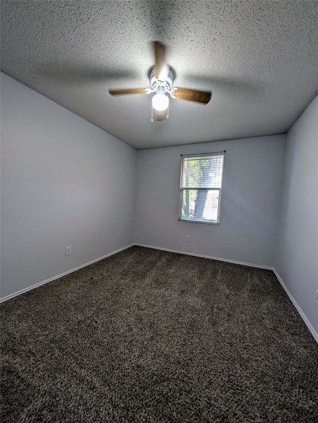 Empty room featuring a ceiling fan, dark colored carpet, baseboards, and a textured ceiling | Image 16