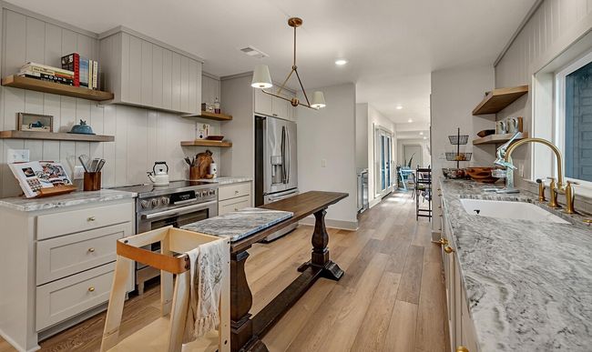 Kitchen featuring open shelves, stainless steel refrigerator with ice dispenser, light wood finished floors, recessed lighting, and light stone countertops | Image 13