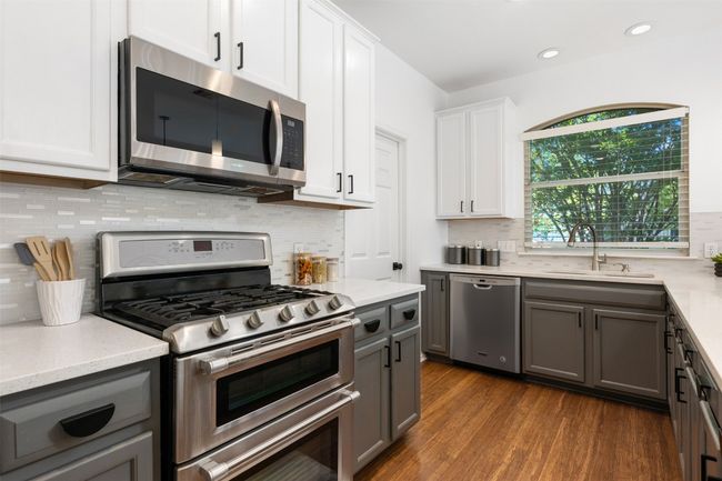 Kitchen with gray cabinets, dark wood-style flooring, a sink, and stainless steel appliances | Image 11