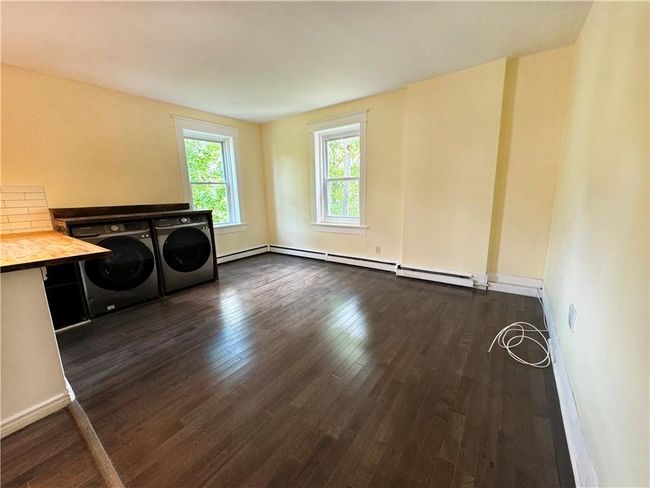 Clothes washing area featuring dark wood-type flooring, baseboard heating, and separate washer and dryer | Image 6