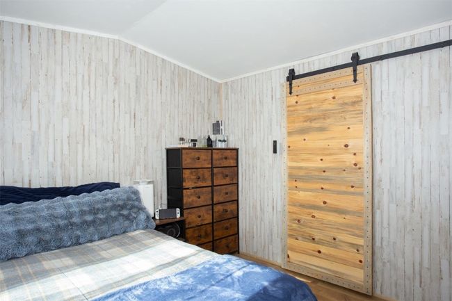 Bedroom featuring a barn door and vaulted ceiling | Image 9